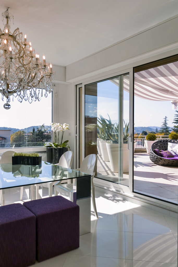interiors shots of a modern dining room with glass dining table and two purple hassock overlooking on the terrace