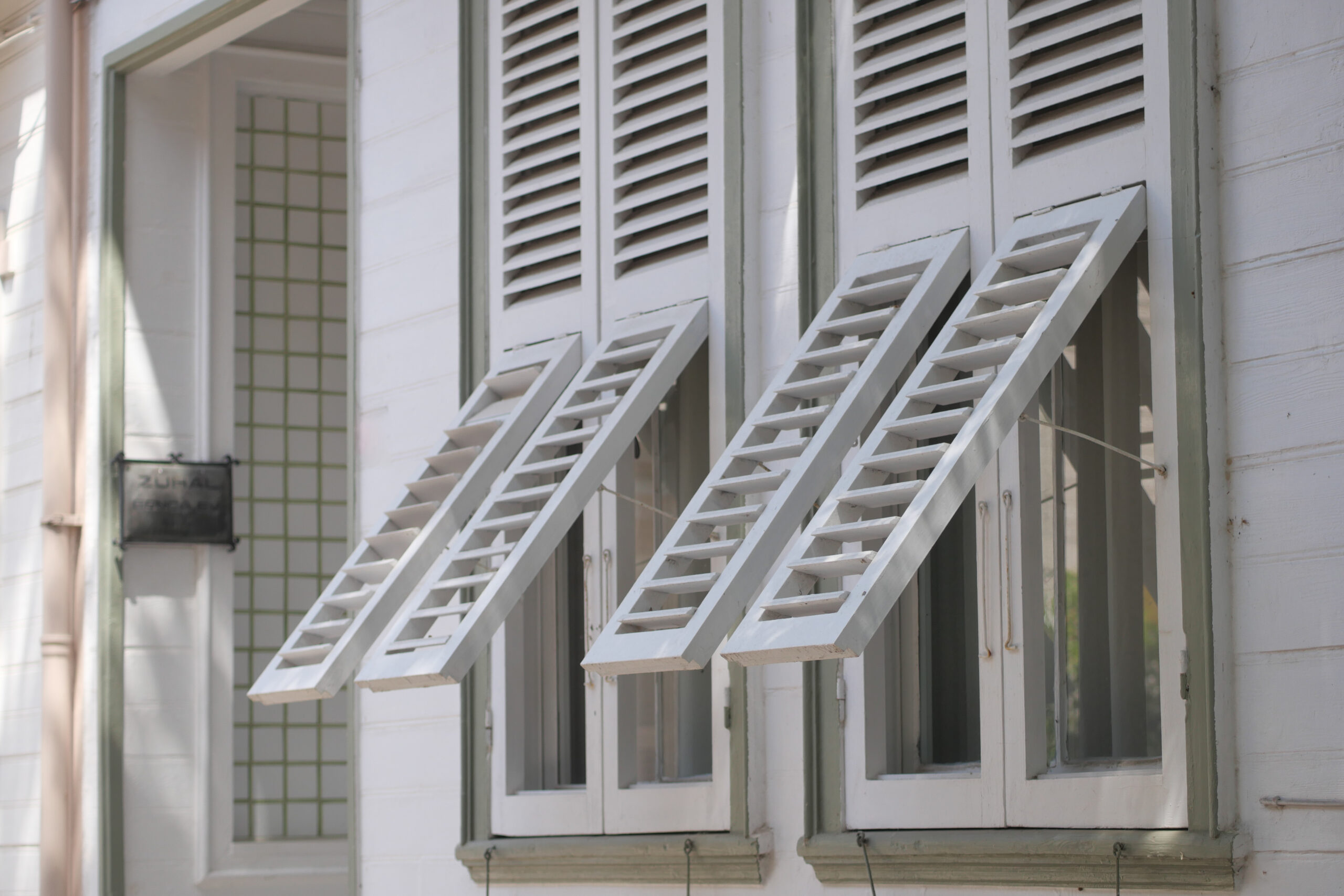 Two wooden shutters are open wide, showcasing the warm sunlight.