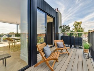 Bright wooden balcony with metal railings, wooden chair and door